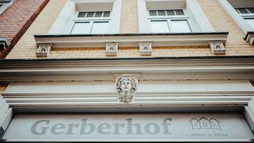 Gerberhof Erfurt's classic facade features a symmetrical design with a decorative stone relief above the entrance.