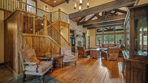 Un vaste espace de vie agrémenté d’un escalier en bois, d’une cheminée en pierre et de sièges confortables.
