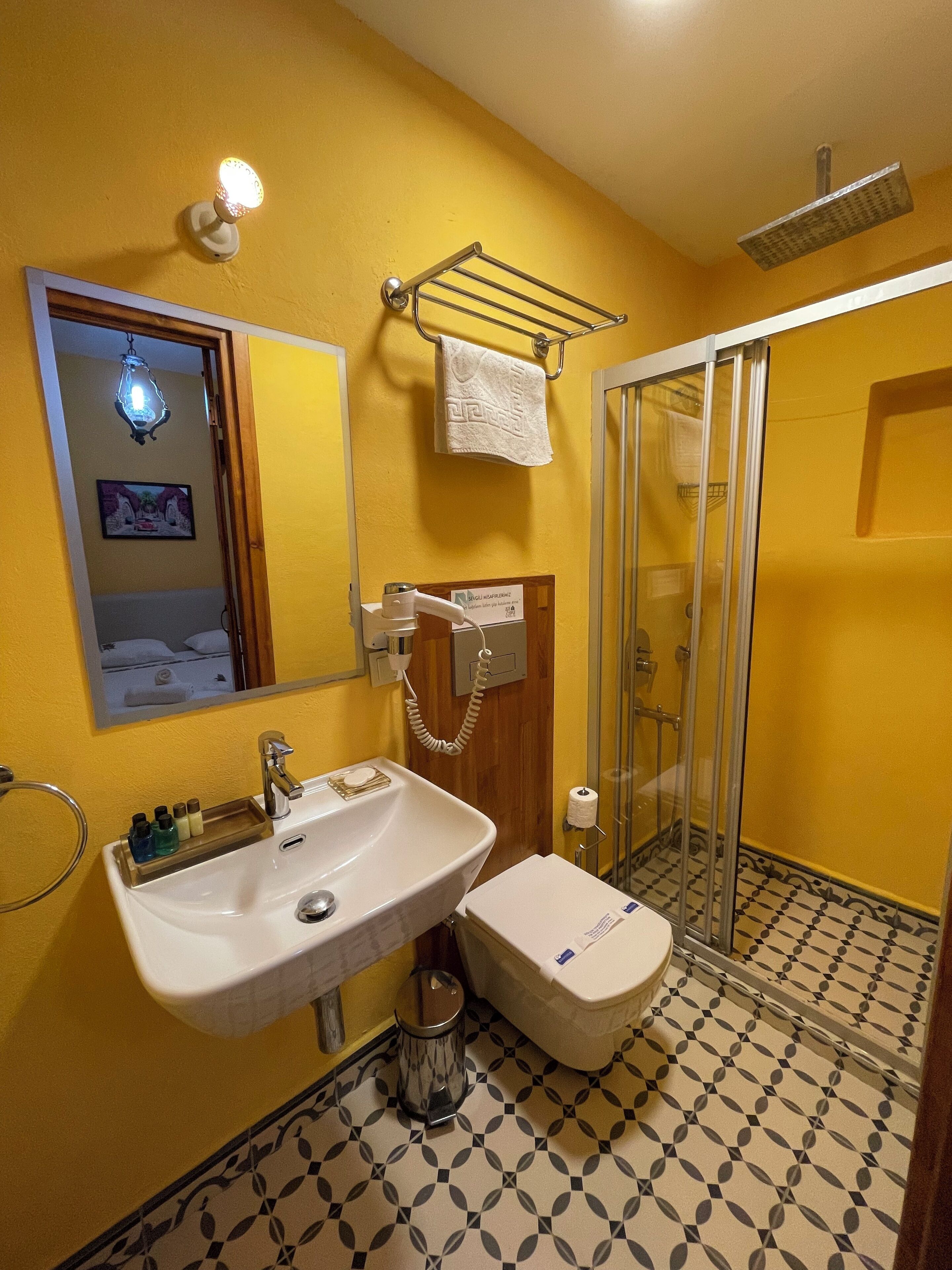 Un baño con lavamanos, espejo, toallero y cabina de ducha de vidrio.