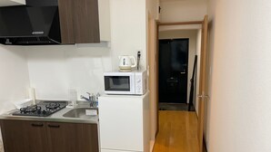 Une cuisine de taille réduite équipée d’une cuisinière à gaz, d’un four à micro-ondes et d’un évier.