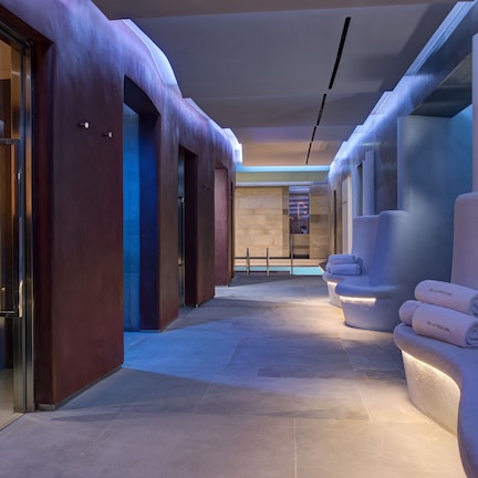 A modern hotel corridor with a spa area, including a massage chair and towels.