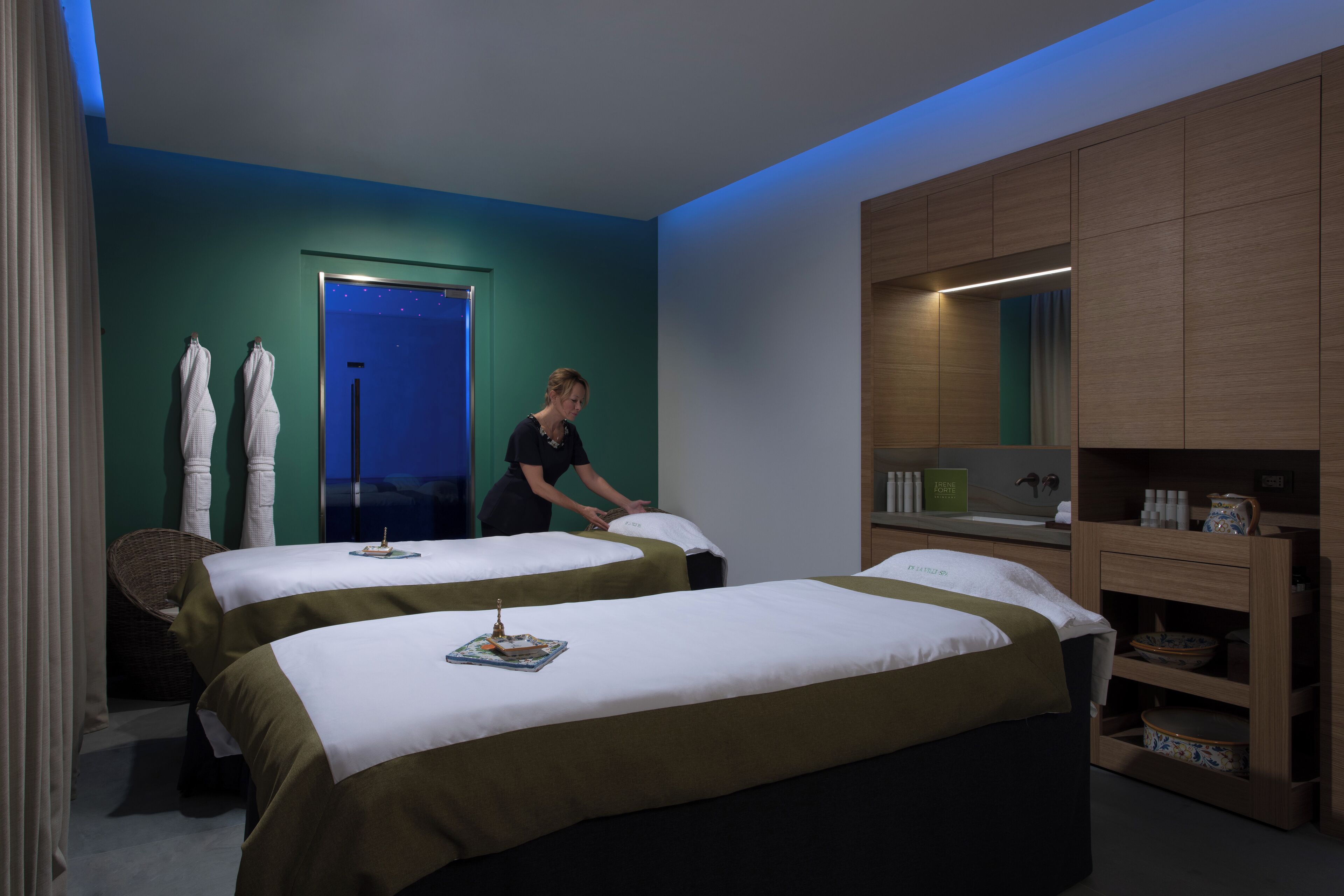 A hotel room with two beds, a bathroom, and a minibar.