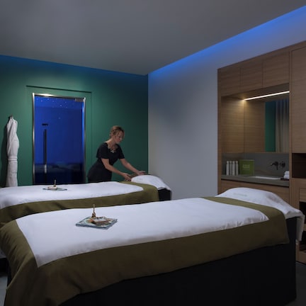 A hotel room with two beds, a bathroom, and a minibar.