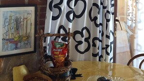 A cozy dining area with a stone wall, a table with a yellow tablecloth, a basket of snacks, and a framed picture.
