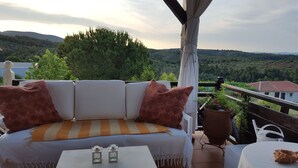 A terrace with a sofa, two small tables, and potted plants.