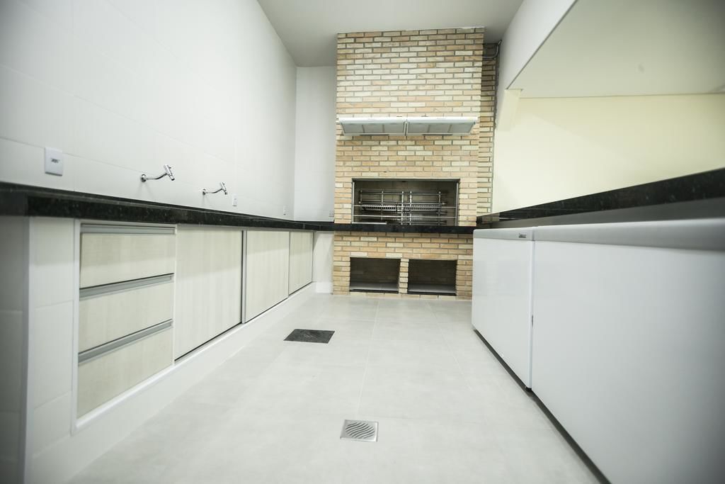 A modern kitchen with white cabinets, a brick accent wall, and a built-in oven.