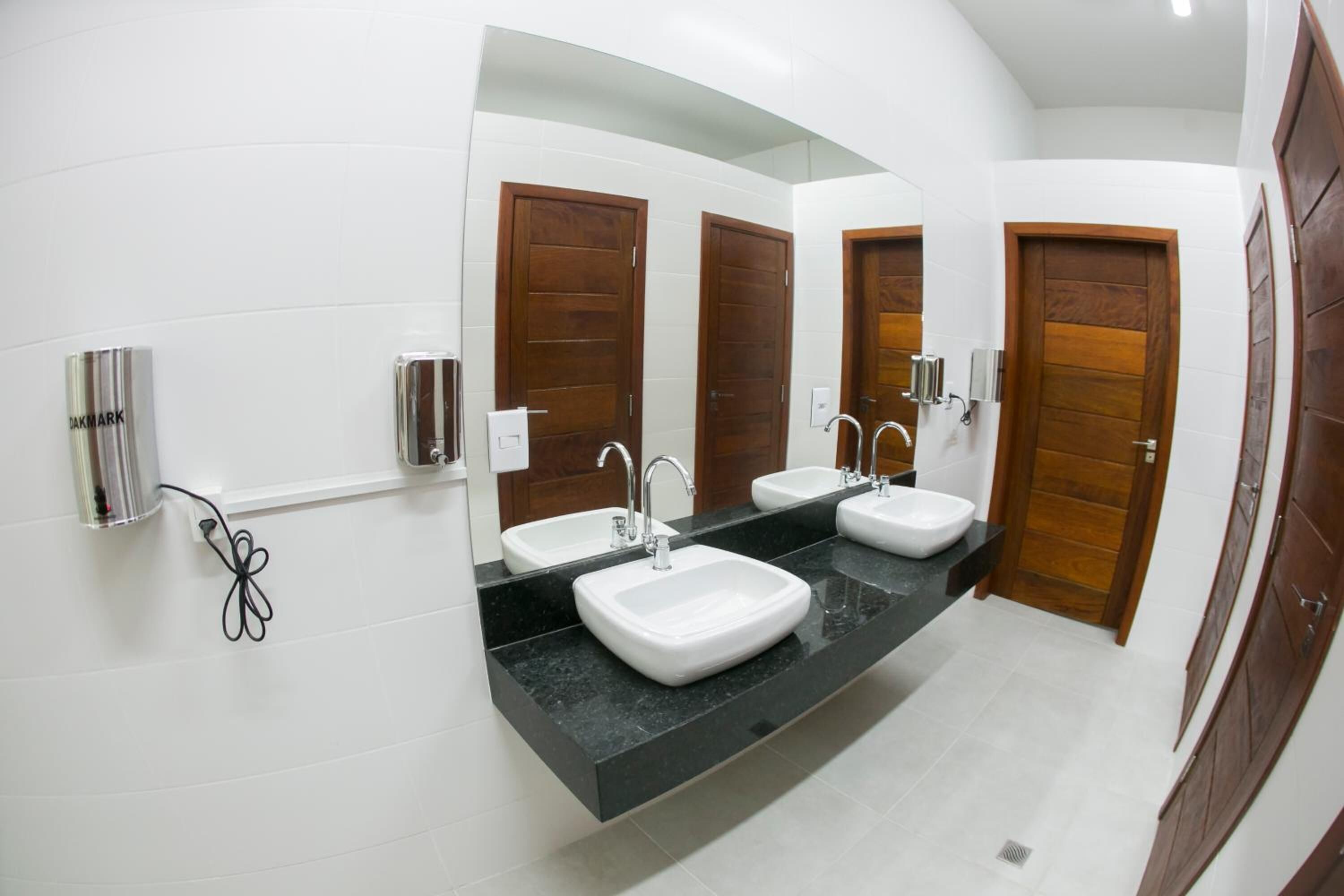 A modern bathroom with two sinks, a large mirror, and wooden doors.