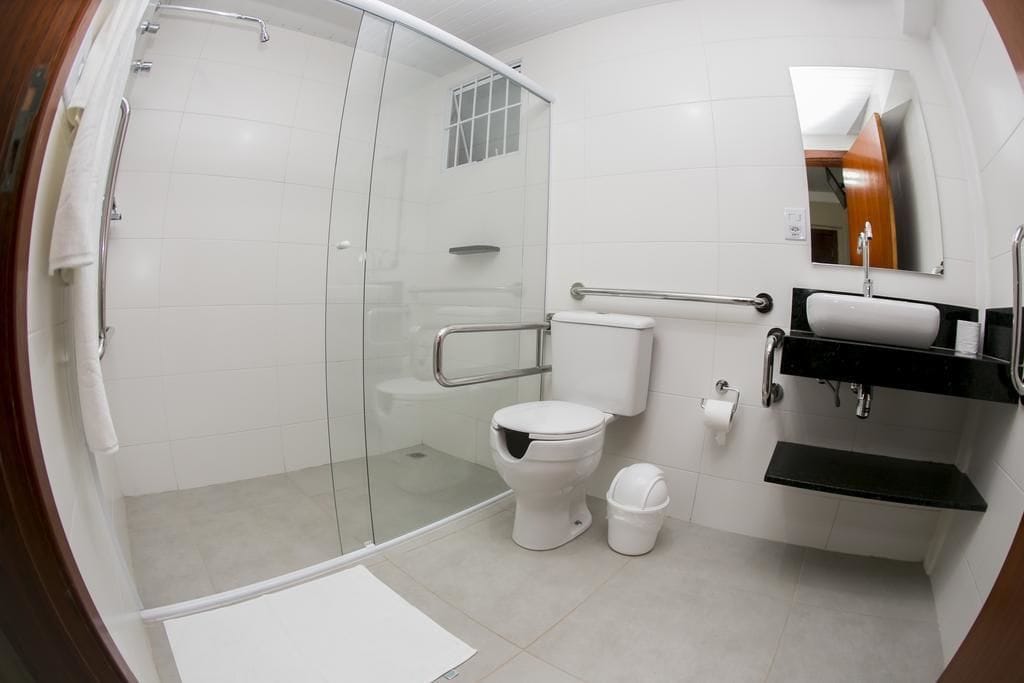 A modern bathroom with a glass-enclosed shower, a white toilet, a sink with a black countertop, and a mirror above the sink.