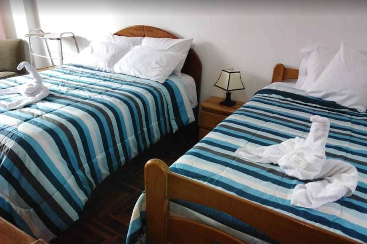 Deux lits avec des draps à rayures, des têtes de lit en bois et des oreillers blancs.