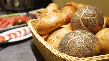Una cesta con varios panes, incluyendo bollos de semillas de amapola y sésamo.