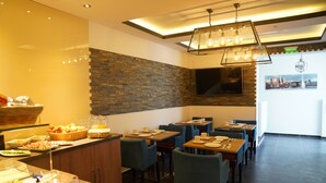 Un restaurante con bufé, sillas azules y una pared de ladrillo.