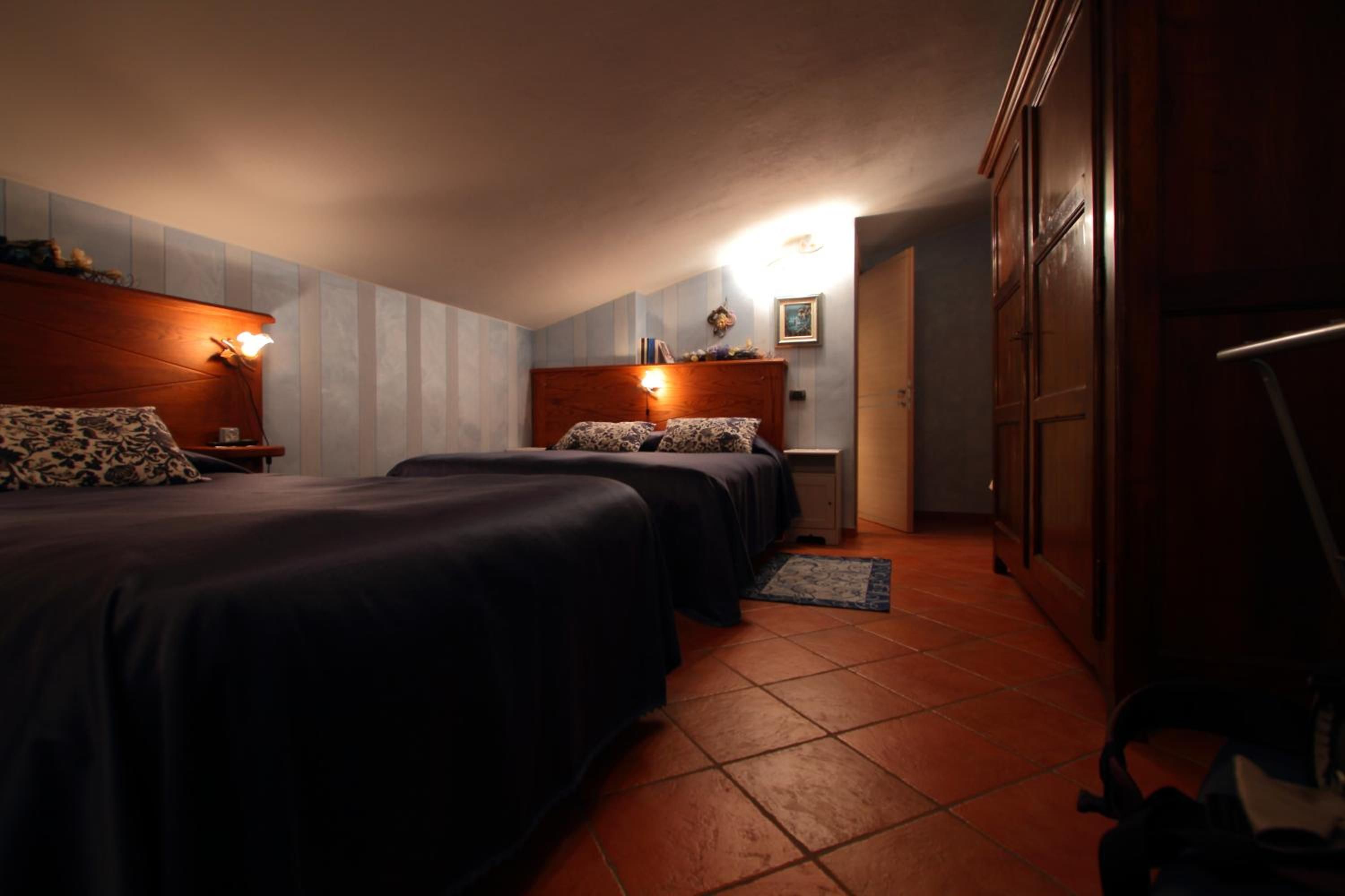 Una habitación de hotel con dos camas, un armario y un pequeño escritorio.