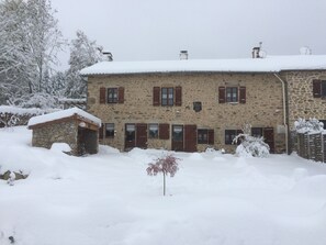 A stone building with multiple windows and doors, surrounded by snow. - Chambre d'hôte la Fessille (Fayet-Ronaye)