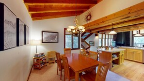 A dining area with a wooden table and chairs, a chandelier, and a map on the wall. - Lodge-Style Stay with Access to Exclusive Golf (Sunriver)