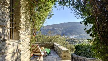 Relax in a serene outdoor seating area overlooking a lush valley and majestic mountain views.