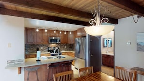 A modern kitchen with wooden cabinets, stainless steel appliances, and a central island with bar stools.