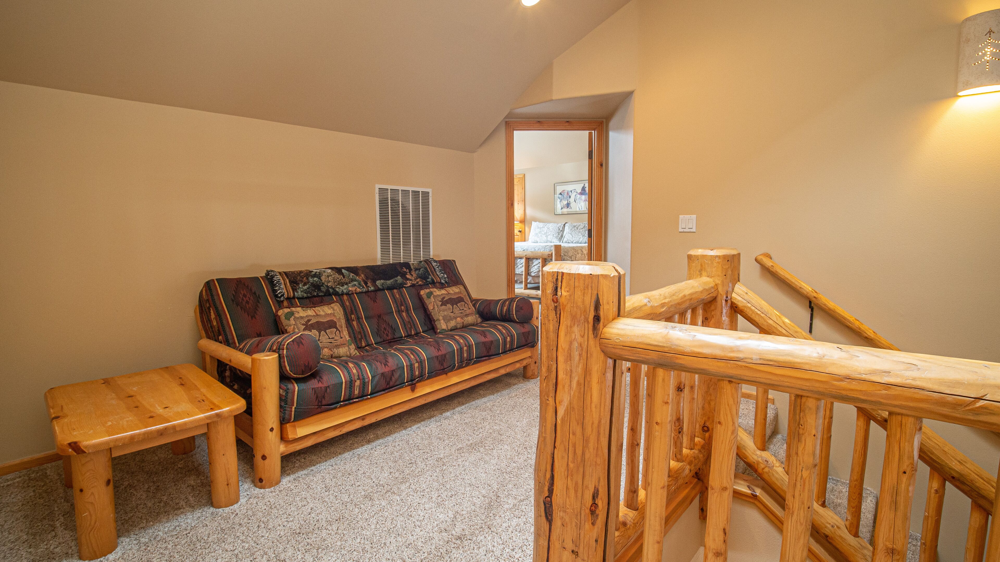Ein gemütliches Zimmer mit einer Holzsofa, einem kleinen Holztisch und einer Holztreppengeländer.