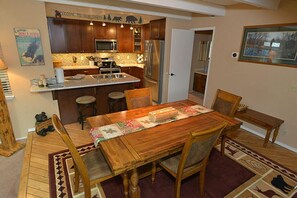 Compact kitchen with a functional layout, featuring a refrigerator, microwave, and island with sink and stools.
