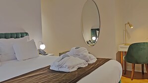 A hotel room with a bed, a bedside table with a lamp, a mirror, and a chair. - Casa dos Ofícios Hotel (Tomar)