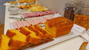Un bufé con diferentes alimentos, incluyendo pan en rodajas, jamón y copos de maíz.