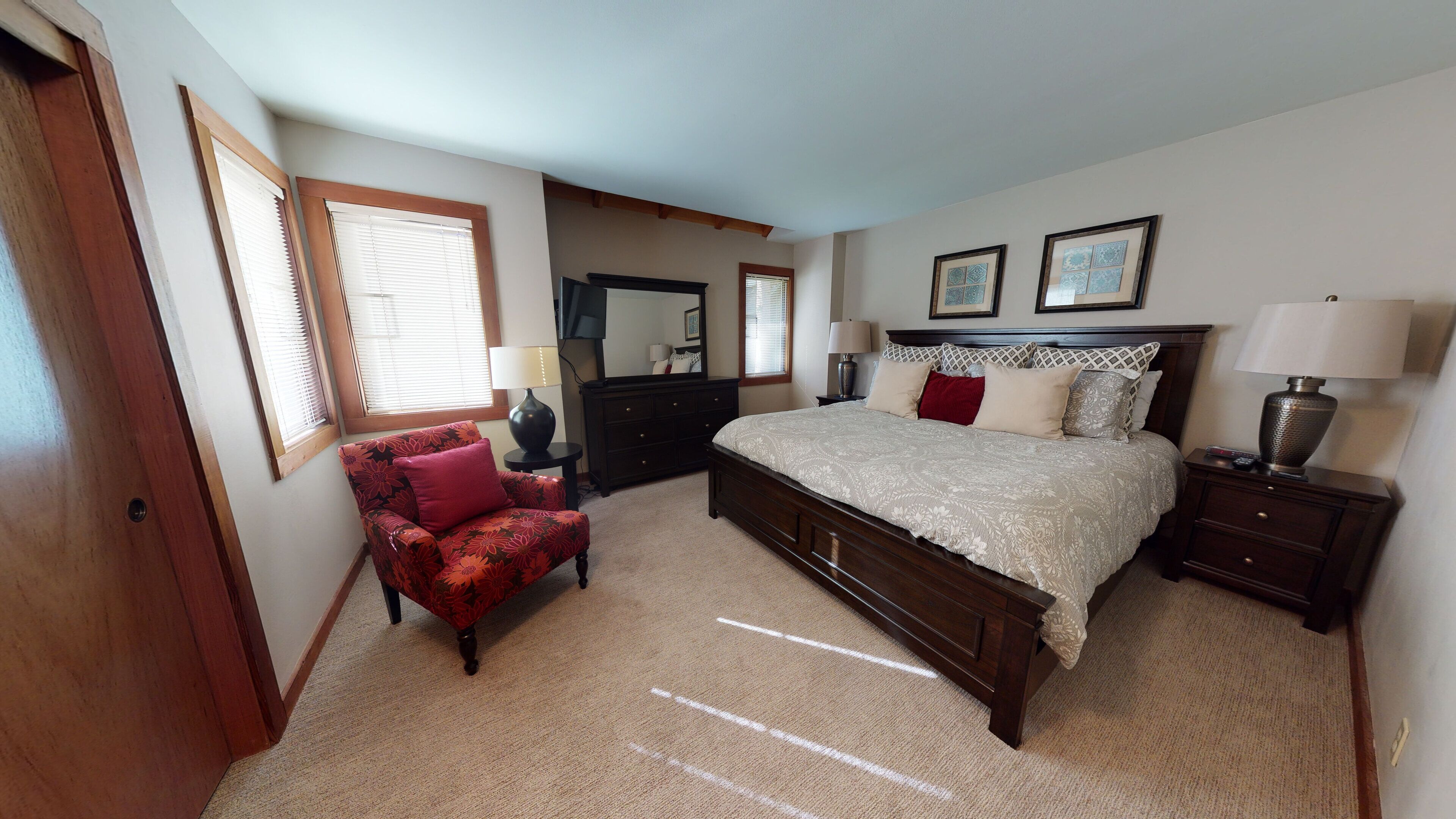 A bedroom with a large bed, a chair, a dresser, and a nightstand.