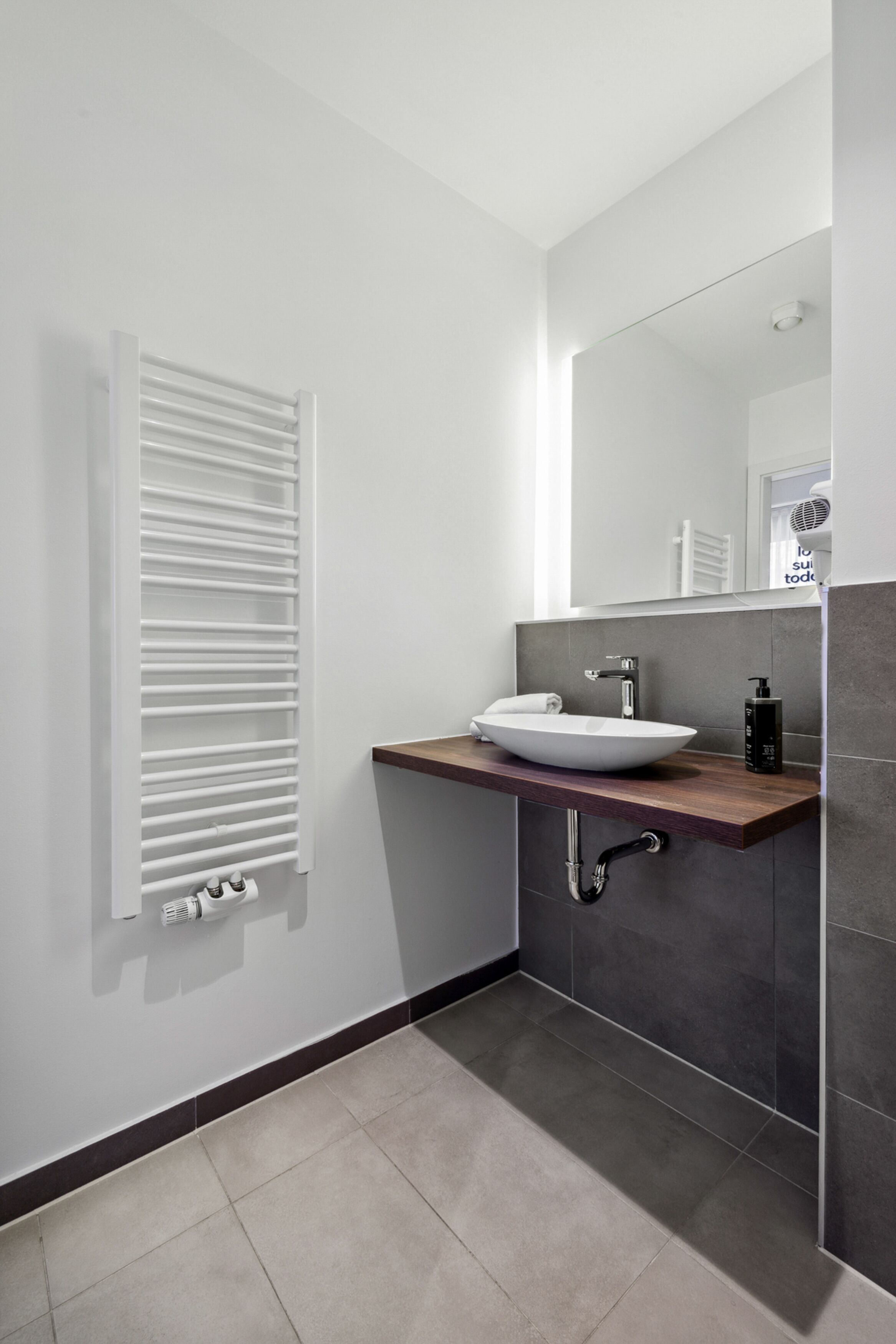 A modern bathroom with a white sink, dark tiles, and a towel rack.
