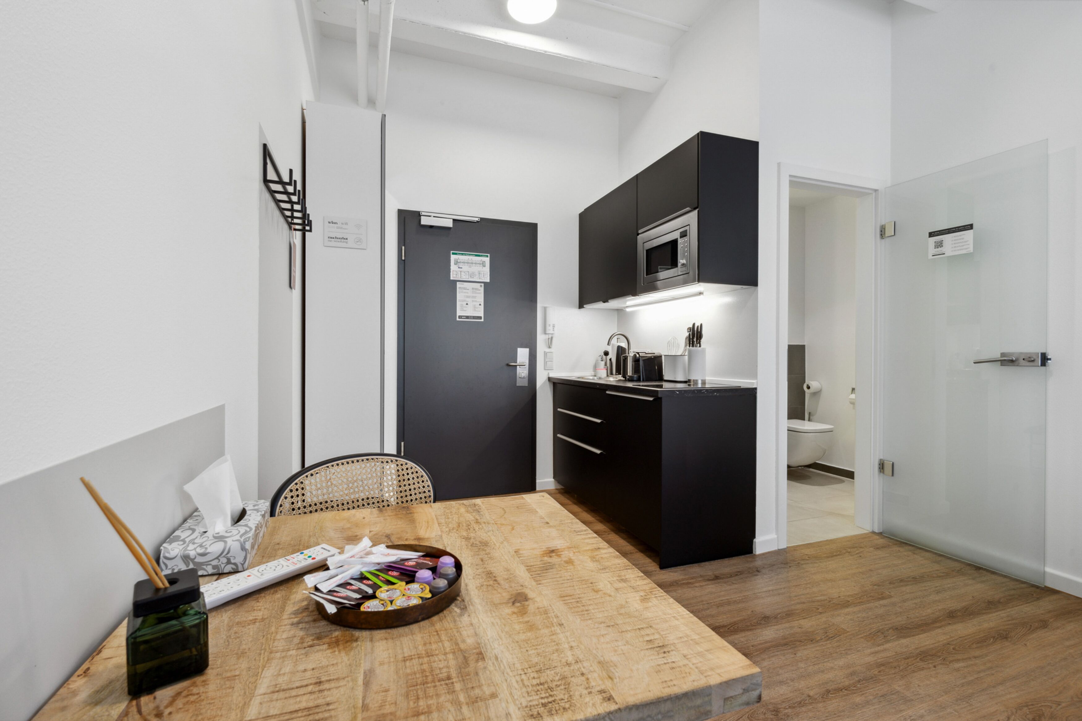 A compact kitchen with modern appliances, a dining area with a wooden table, and a small seating area.