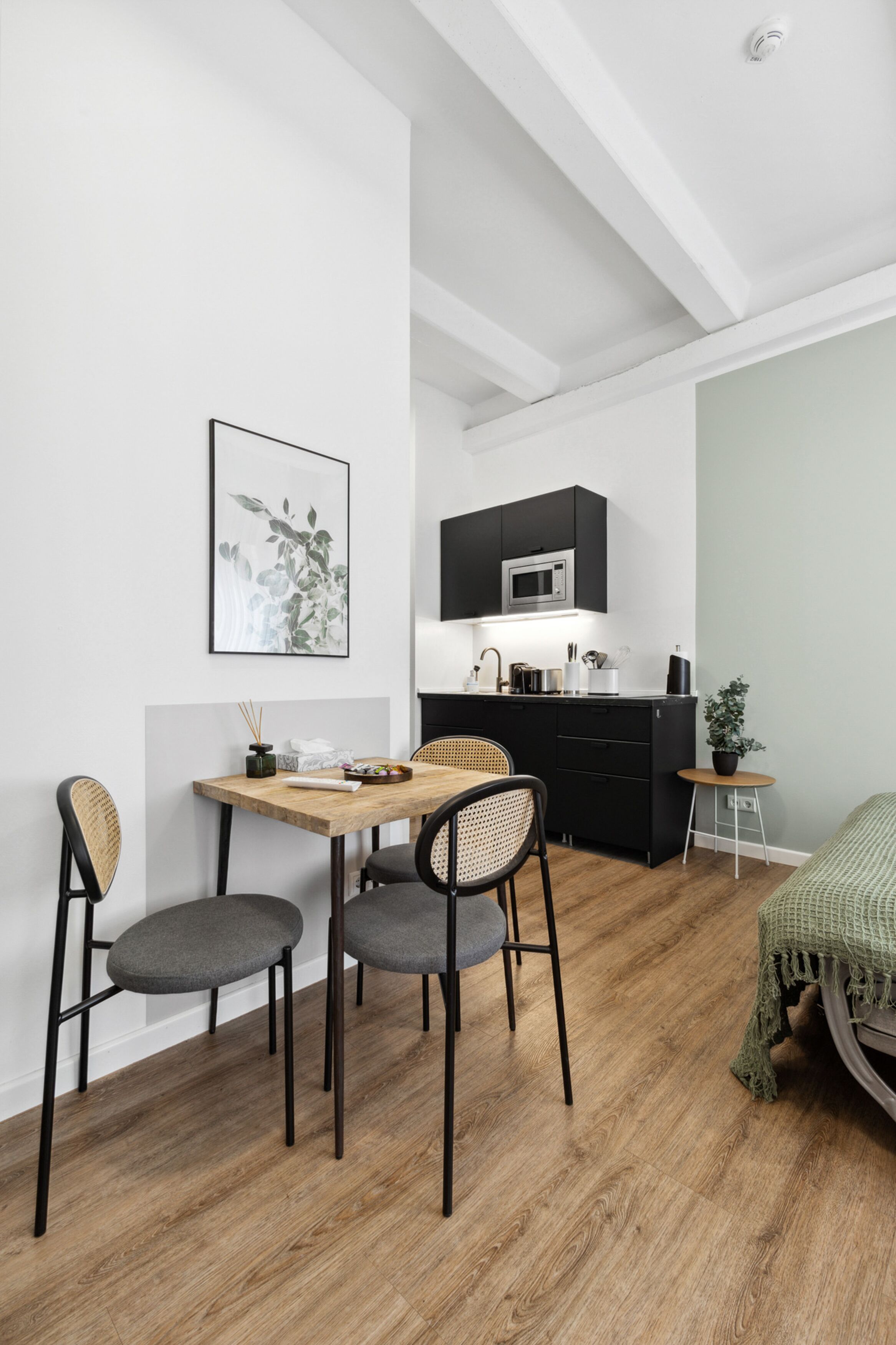 Un espacio habitable moderno y compacto con comedor, kitchenette y una cama.