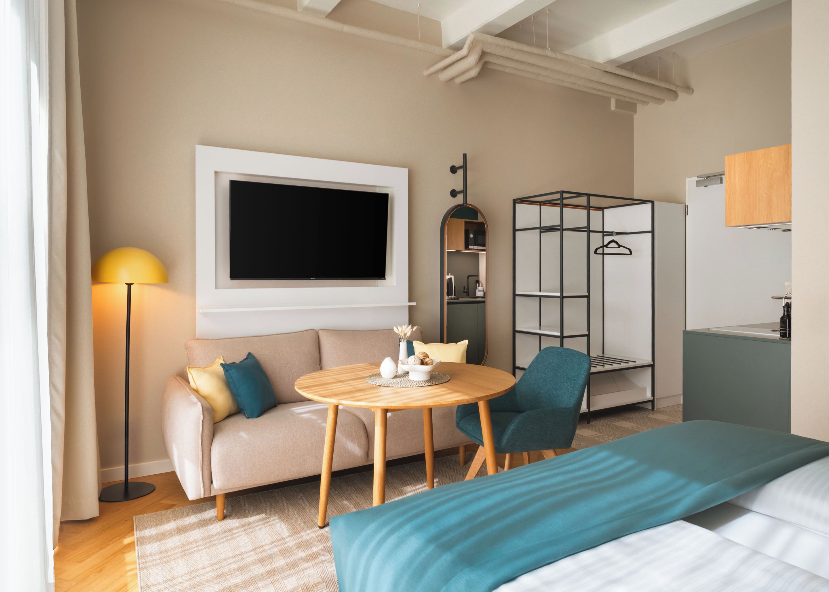 Una habitación de hotel moderna con sofá, una mesa redonda, televisor, armario y cama.
