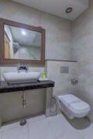 A bathroom with a white sink, a mirror, a toilet, and a shower.