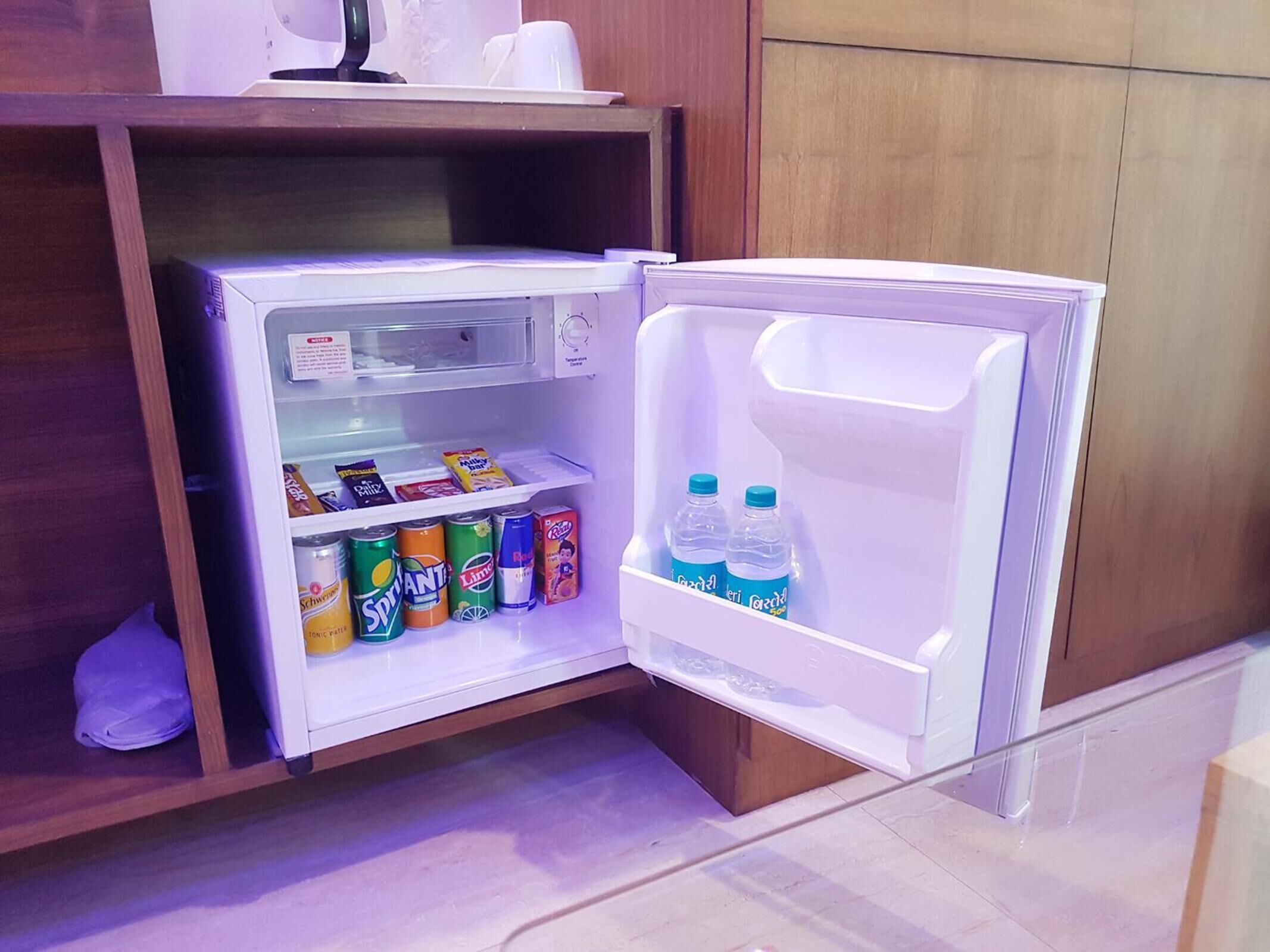 A compact refrigerator with a freezer compartment on top, containing various beverages and snacks.