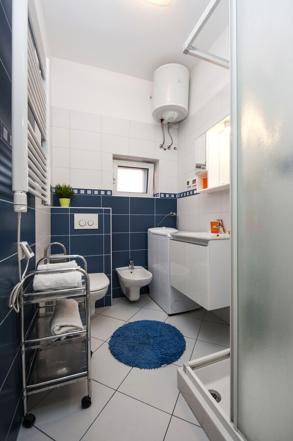 Un baño pequeño con inodoro, bidé, lavamanos y perchero para toallas.