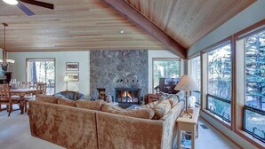 Ein gemütliches Wohnzimmer mit Kamin, großen Fenstern und einer Holzbalkendecke.