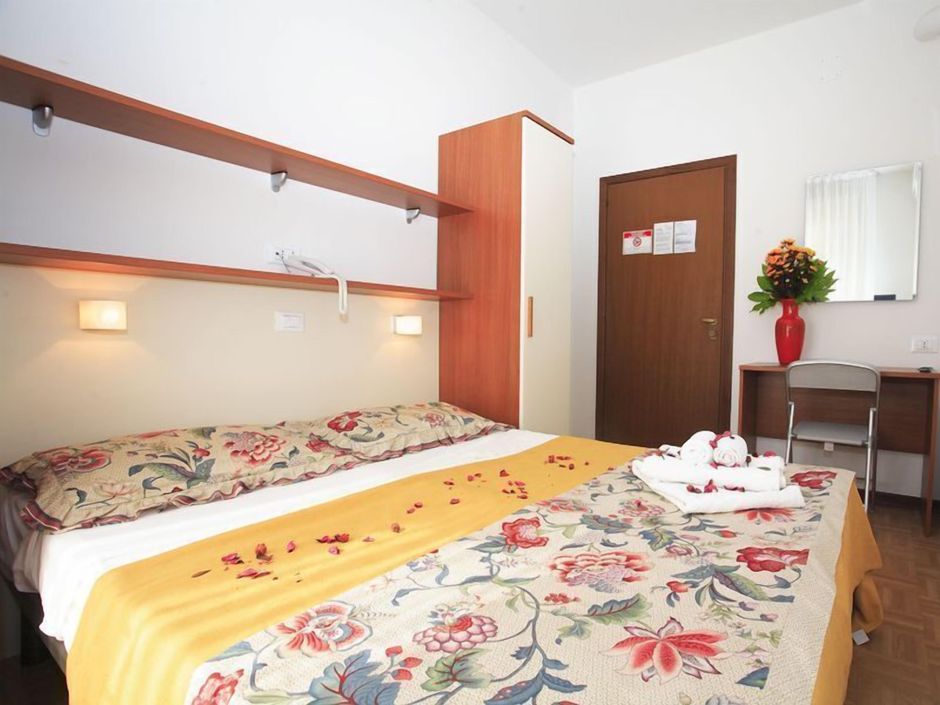 Un dormitorio con cama, mesita de noche, escritorio, silla y espejo.