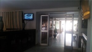 A hallway with a television on the left, a sliding glass door in the center, and a staircase on the right. - Hotel Antar Bechar (Bechar)