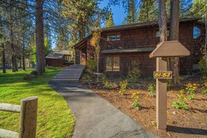 A wooden cabin with a stone foundation, surrounded by a forest.