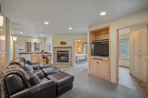 A spacious living room with a fireplace, leather seating, and a television.
