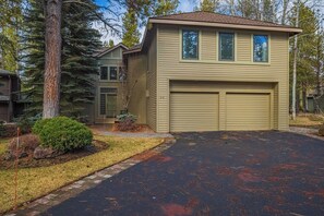 A two-story house with a garage, surrounded by trees and a well-maintained lawn.