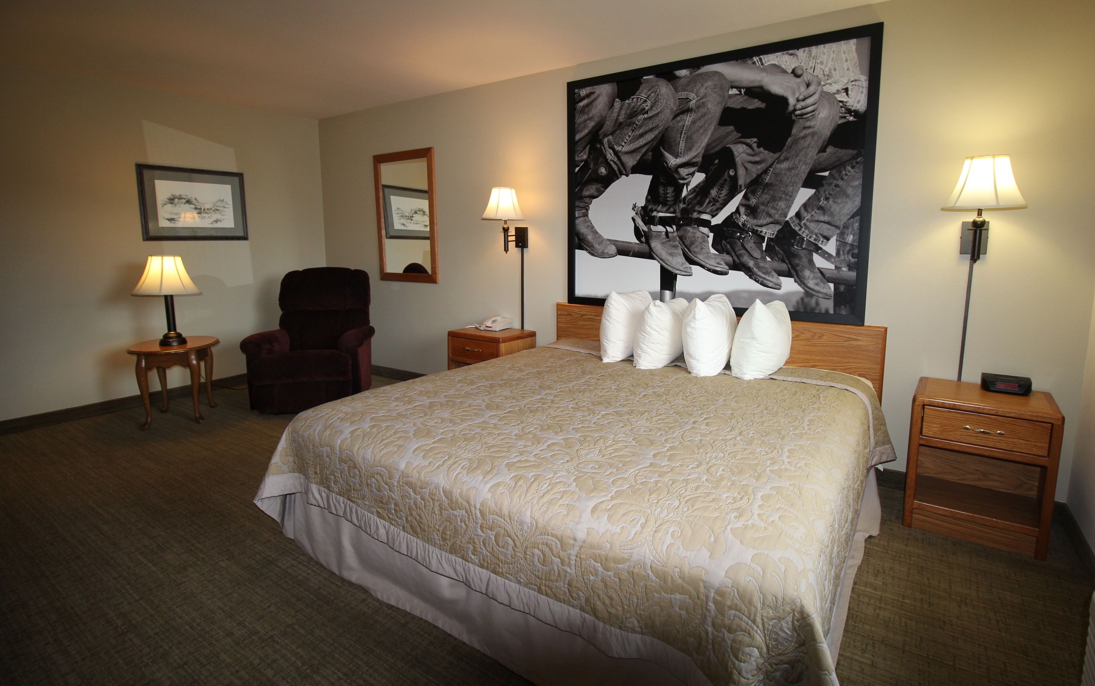 Une chambre d’hôtel avec un grand lit, deux tables de chevet, une chaise, un bureau et deux lampes.