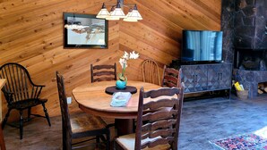 A cozy room with a wooden ceiling, a round wooden table with chairs, a television, and a fireplace. - Marina Access Retreat with Access to The Cove (Bend)