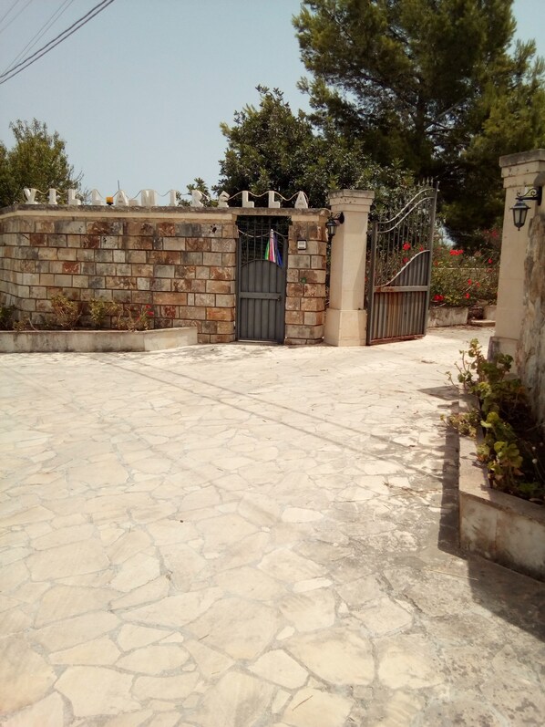 A gated entrance with a stone wall and a metal gate. - B&B Villa Mirella (Pachino)
