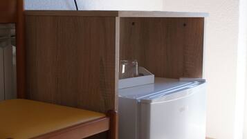 A kitchen area with a white refrigerator, wooden cabinets, and a wooden chair.