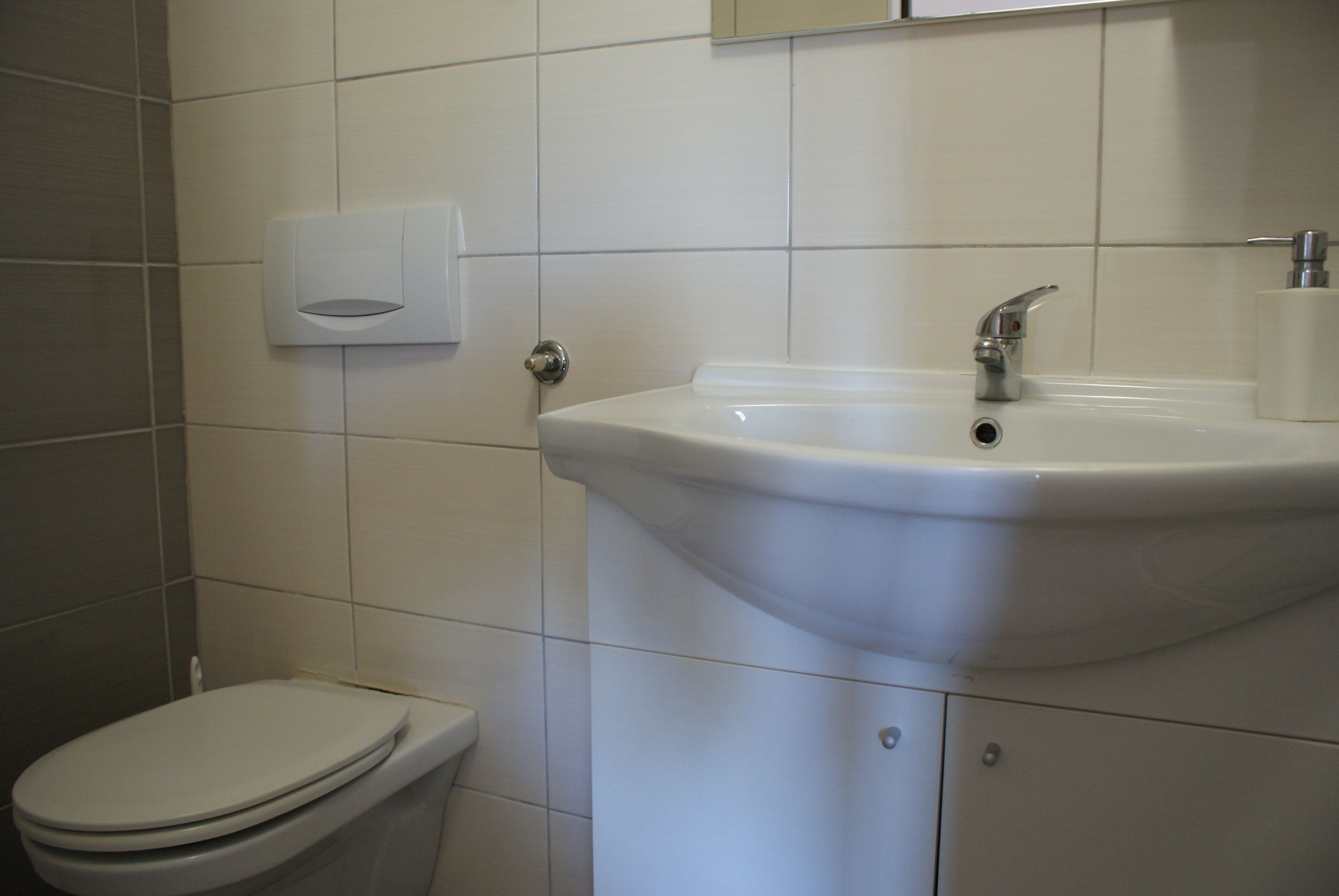 A bathroom with a toilet, a sink, and a paper towel dispenser.