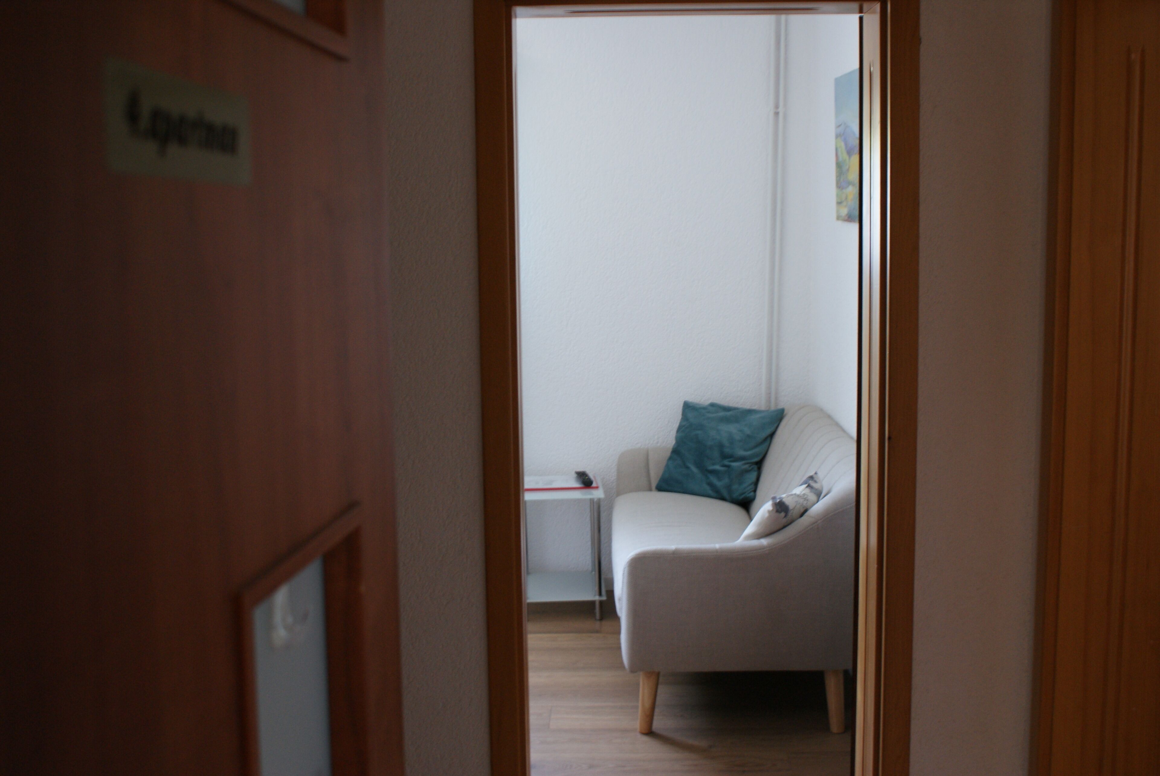 A doorway leading to a room with a white sofa, a small table, and a sign on the wall.