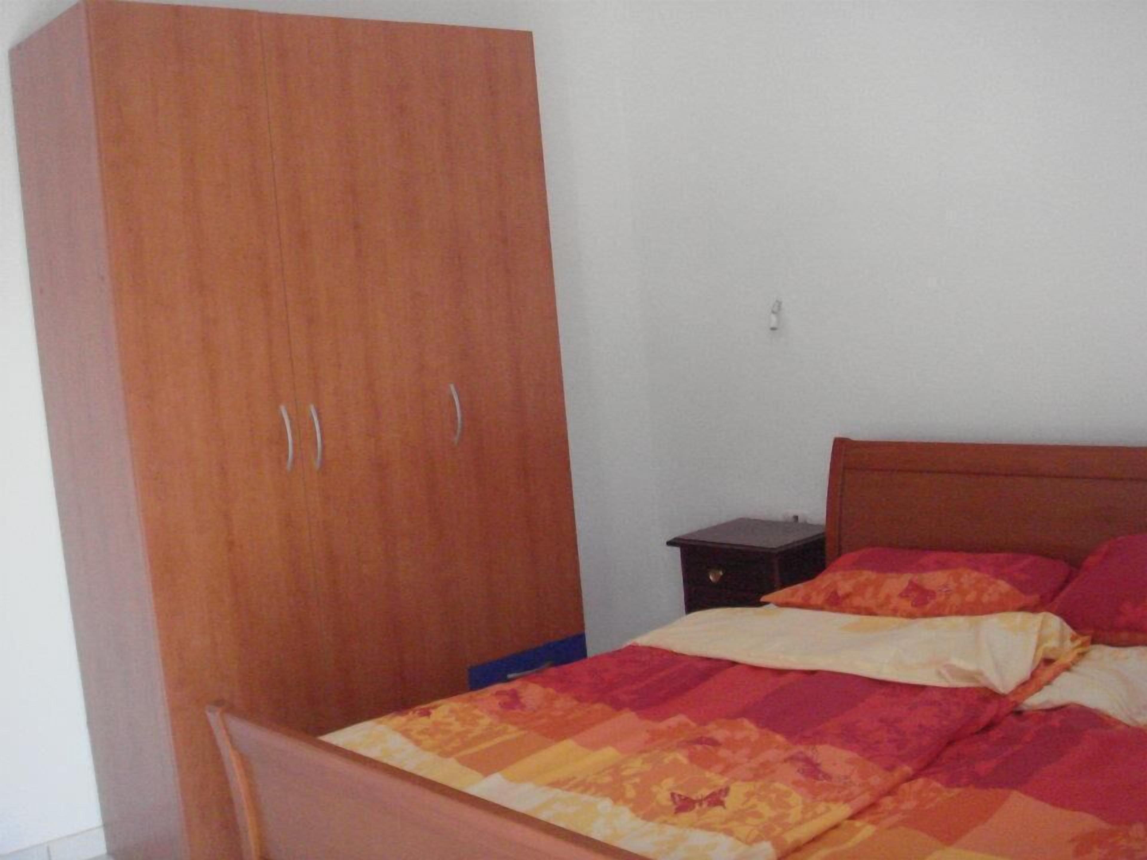 Un dormitorio con un armario de madera, una cama con colcha estampada y una mesita de noche.