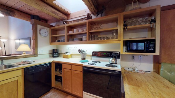 A compact kitchen with wooden cabinets, a microwave, a stove, and a coffee maker. - Lodge Style Condo with Access to Exclusive Golf (Sunriver)