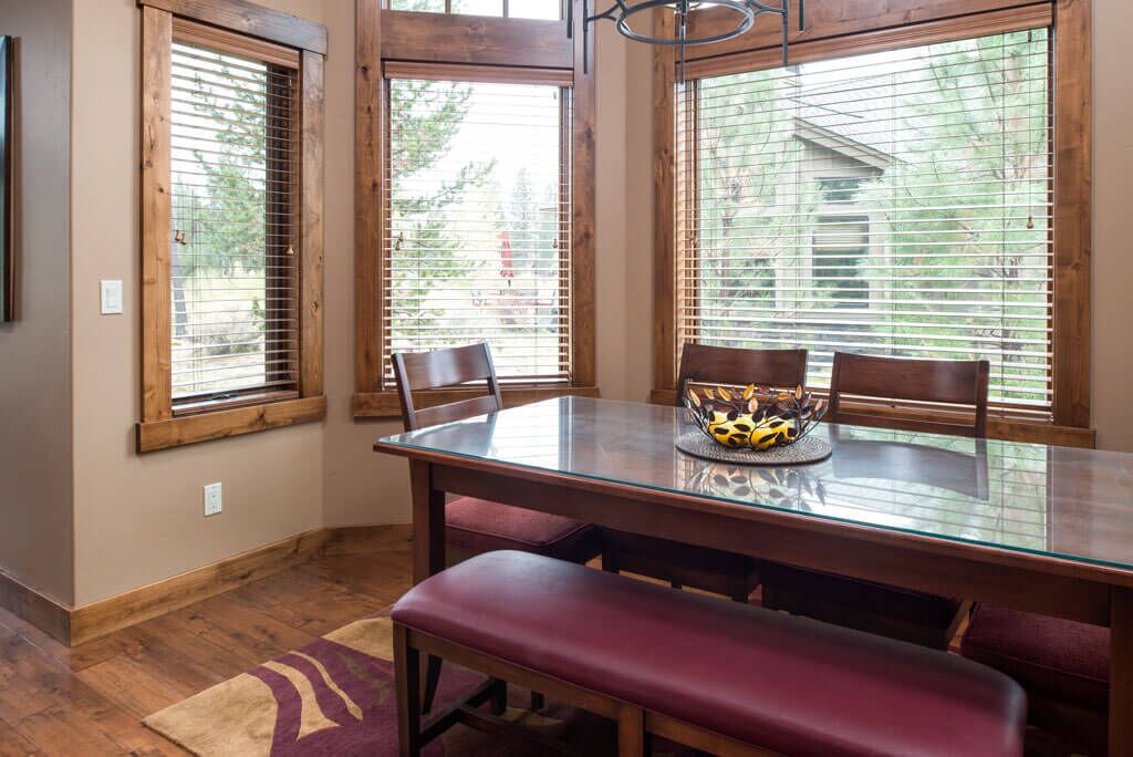 A dining area with a glass table, wooden chairs, and a bench.