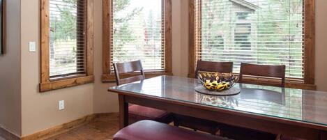A dining area with a glass table, wooden chairs, and a bench.