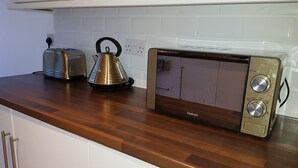 Una cocina con tostadora, hervidor y microondas sobre una encimera de madera.