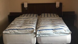 A double bed with striped bedding, a dark headboard, a wall-mounted painting, and a hanging light fixture.